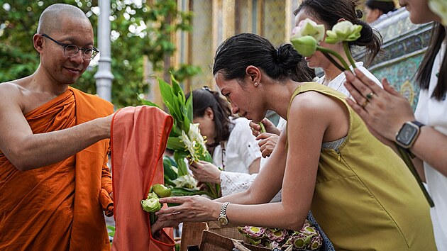 Thajci nabzej kvtiny buddhistickm mnichm bhem kvtinovho obadu v chrmu v thajskm Bangkoku. (11. ervence 2025)