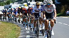 Remco Evenepoel v bílem dresu si kontroluje pozici  na pedních píkách...