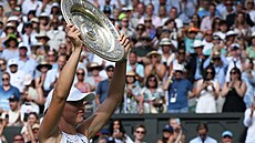 Iga wiateková ukazuje fanoukm trofej pro vítzku Wimbledonu.