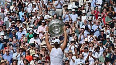 Iga wiateková ukazuje fanoukm trofej pro vítzku Wimbledonu.