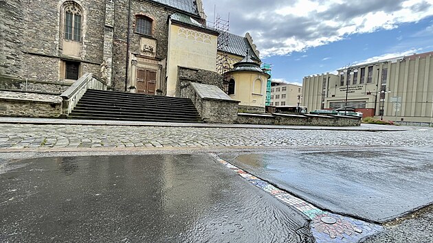 Mozaika u kostela svatho Bartolomje nenpadn oivuje pokozen chodnk a stv se soust historickho centra Pardubic. (22. ervence 2025)