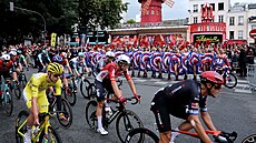 Tadej Pogaar projídí s pelotonem okolo tanenic z Moulin Rouge.