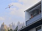 Hasiské letadlo hasí lesní poár, zatímco turisté z balkonu sledují dní v...