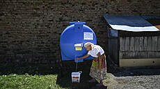 Star�í �ena plní kbelík vodou z nádr�e instalované na ulici ve vesnici Gorna...