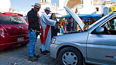 Kní pokropí auta svcenou vodou a poté majitelé rozlévají na kola a na zem...
