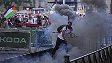 Demonstrant odhazuje dýmovnici mezi poni�enými pl�tky.