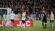 Hlavní sudí Marek Radina po konzultaci s asistentem u videa udluje ervenou...