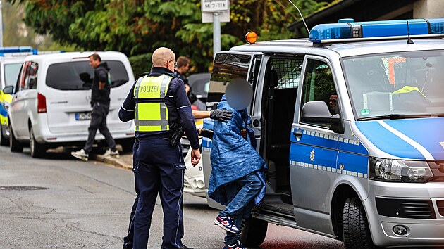 Policist odvdj chlapce k policejnmu autu pot, co byla jeho adoptivn matka Iris Stalzerov nalezena pobodan v jejich byt. (7. jna 2025)