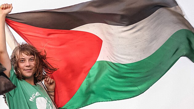 Greta Thunbergová gestikuluje vedle palestinské vlajky na lodi, která je...