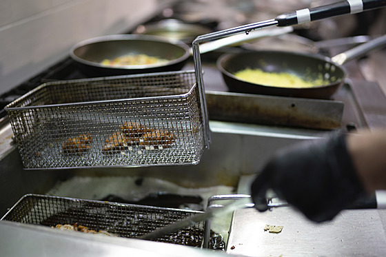 Kucha v erných rukavicích pipravuje smaené jídlo ve fritéze. (12. bezna...