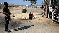 �len Hamásu v Pásmu Gazy stojí na strá�i, zatímco vozidla �erveného k�í�e...