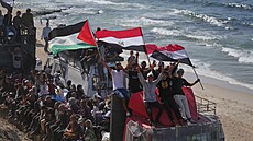 Vysídlení Palestinci jedou na nákladních vozech naloených svými vcmi a mávají...