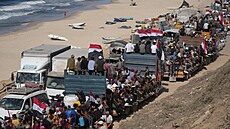 Vysídlení Palestinci jedou na nákladních vozech naloených svými vcmi a mávají...