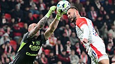 Zlínský branká Stanislav Dostál vyráí mí ped Erikem Prekopem ze Slavie.