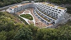 Stavba zasazená do lenitého terénu svým tvarem reaguje na okolní podmínky.