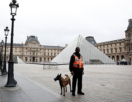 Bezpe�nostní pracovník se psem stojí poblí� sklen�né pyramidy Louvru, který...