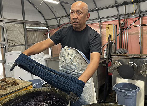 Mistr barví Joshiharu Okamoto ukazuje, jak barví tkaninu indigem pro výrobu...