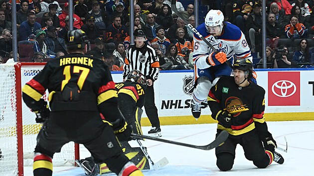 David Tom�ek nadskakuje v brankovi�ti Vancouveru. Situaci sleduje i Filip Hronek.