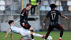 Sparanský obránce Adam evínský se snaí udret balon balon ped skluzujícím...