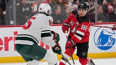 Jack Hughes z New Jersey Devils úto�í v zápase s Minnesota Wild, hlídá ho David...