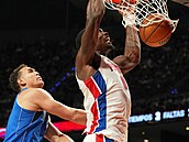 Dwight Powell (Dallas) jen pihlíí, jak rozjetý Jalen Duren (Detroit) smeuje.