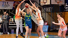 Emese Hofová z USK Praha pihrává v obklíení hráek Basketu Ostrava.