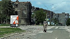 Obyvatelka jde po ulici poblí� budov po�kozených ruskými vojenskými údery ve...
