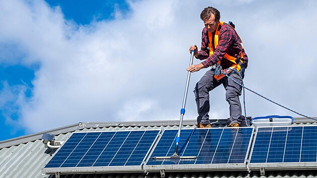 Dlník istí solární panely na stee pedmstského domu v jiní Tasmánii....