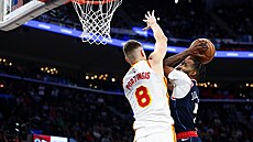 Derrick Jones Jr. se sna�í dostat ke ko�i p�es blokujícího Kristapse Porzingise.