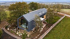 Protáhlá silueta domu kopíruje linii buk uprosted pozemku, koní u terénního...