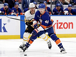 Obránce New York Islanders Matthew Schaefer (v pop�edí) kontroluje puk, napadá...