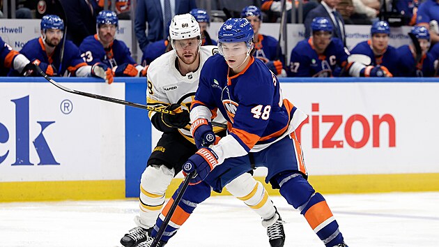 Obr�nce New York Islanders Matthew Schaefer (v pop�ed�) kontroluje puk, napad� ho David Pastr��k z Bostonu.