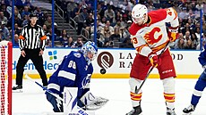 Branká� Tampy Bay Andrej Vasilevskij zasahuje proti te�i Adama Klapky z Calgary.