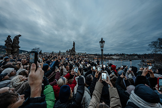 Výjev jako z pohádky. Pražský lampář rozsvěcí Karlův most, pro turisty je atrakce