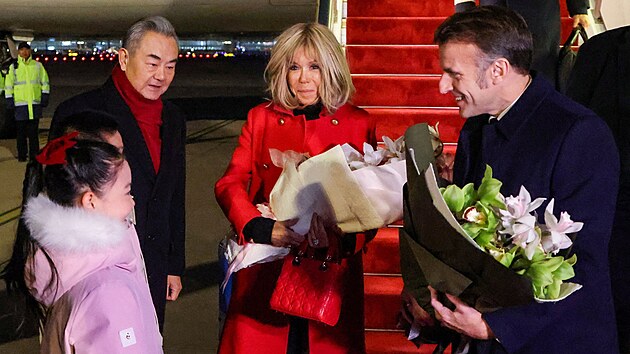 ��nsk� ministr zahrani�� Wang I v�t� francouzsk�ho prezidenta Emmanuela Macrona a jeho man�elku Brigitte Macronovou po jejich p��letu na leti�t� v Pekingu. (3. prosince 2025)