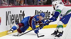 Filip Hronek u mantinelu obírá o puk Nathana MacKinnona.