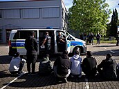 Podez�elí nelegální migranti sedí na zemi poté, co je zadr�ela n�mecká policie....