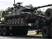 Vojenský nákladní v�z p�evá�í tank po silnici uprost�ed smrtících st�et� mezi...