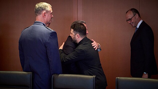 Ukrajinsk� prezident Volodymyr Zelenskyj obj�m� americk�ho zvl�tn�ho vyslance pro Bl�zk� v�chod Steva Witkoffa vedle zet� americk�ho prezidenta Donalda Trumpa Jareda Kushnera. (14. prosince 2025)