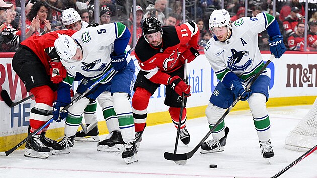 �to�n�k Vancouveru Brock Boeser s pukem na hokejce, br�n� ho Stefan Noesen z New Jersey Devils.