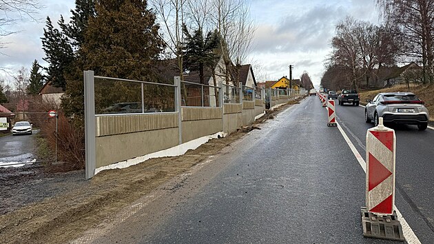 Nov� protihlukov� st�na v Prav�kov� na Pelh�imovsku u� stoj�. Zejm�na obyvatel� dom� hned za n� si kone�n� u�ij� trochu klidu. Proto�e je st�na bl�zko u dom�, je prosklen�. Foto bylo po��zeno kr�tce p�ed dokon�en� prac�. Nyn� u� je vesnice pr�jezdn� bez omezen�.