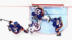 Branká� NY Islanders David Rittich zasahuje proti Samu Carrickovi z NY Rangers.