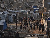 Palestinci krá�í po ulici kolem stanového tábora obklopeného budovami zni�enými...