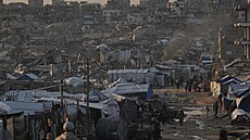 Palestinci krá�í po ulici kolem stanového tábora obklopeného budovami zni�enými...