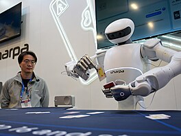 Lidé sledují, jak robot Sharpa North rozdává karty v pokeru na stánku...