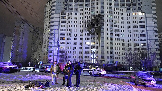 Policist� stoj� u t�la p�ed po�kozen�m v�cepodla�n�m bytov�m domem po rusk�m �toku v Kyjev�. (9. ledna 2026)