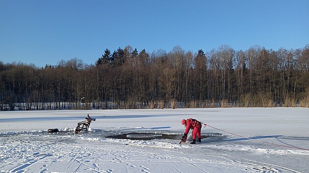 Hasi�i roz�ez�vaj� led, aby bylo mo�n� stroj z rybn�ku Sp�leni�t� vyt�hnout. (8. ledna 2026)
