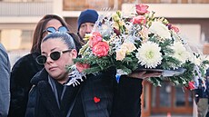 Lidé nosí kv�tiny k památníku, který p�ipomíná smrtelný po�ár b�hem...