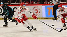 T�inecký obránce Tomá� Kundrátek se natahuje po puku. Sleduje ho David Musil.