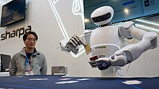 Lidé sledují, jak robot Sharpa North rozdává karty v pokeru na stánku...